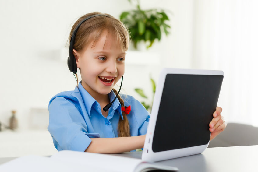 Smart little schoolgirl with digital tablet in a classroom. Child in an elementary school. Education and learning for kids.