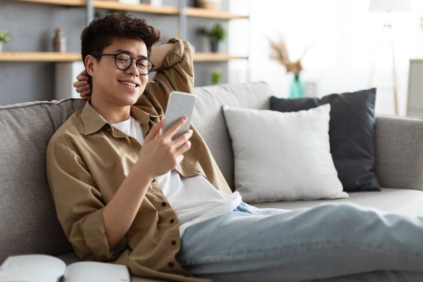 young man looking at smartphone on couch