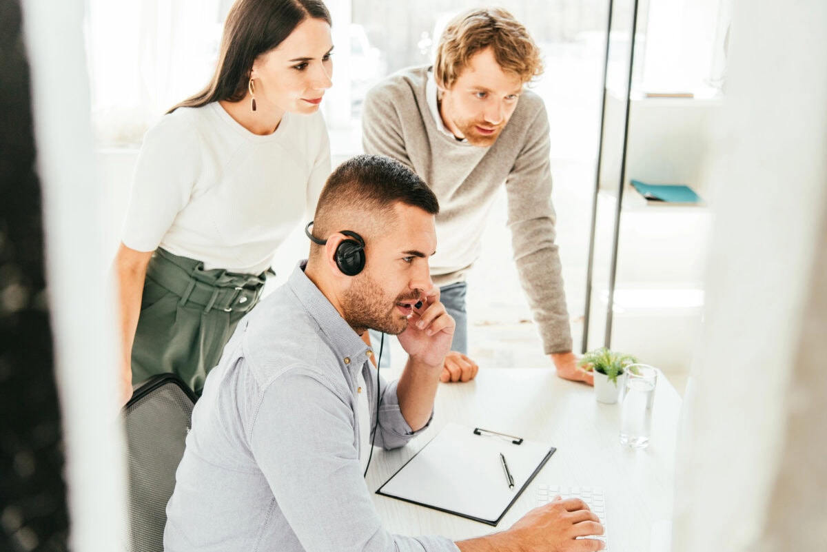 Selective focus of broker in headset talking near coworkers in office