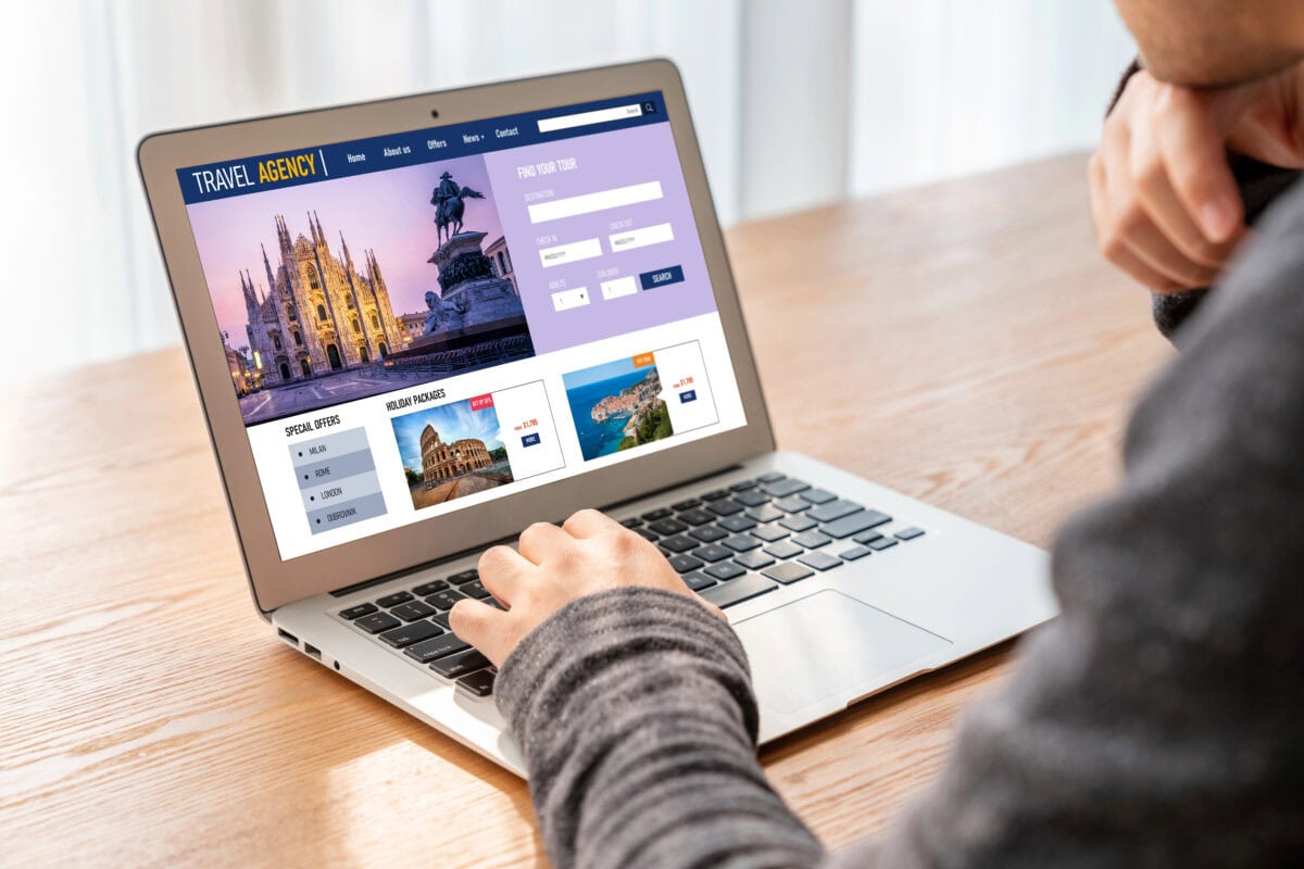 Person browsing a travel agency website on a laptop, showing images of destinations and search options.