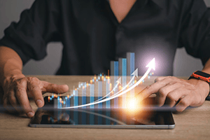 Person using a tablet displaying 3D bar graphs and an upward arrow, suggesting data growth or financial success.