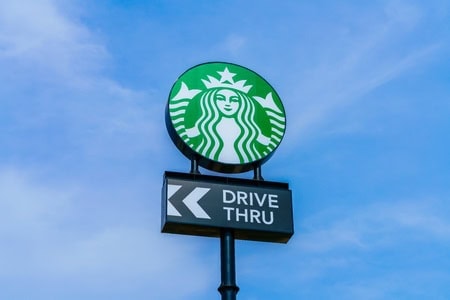 Starbucks drive-thru sign with logo against a blue sky backdrop.